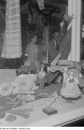 Besucher der Herbstmesse 1953 an einer Glasvitrine mit kunsthandwerklichen Erzeugnissen