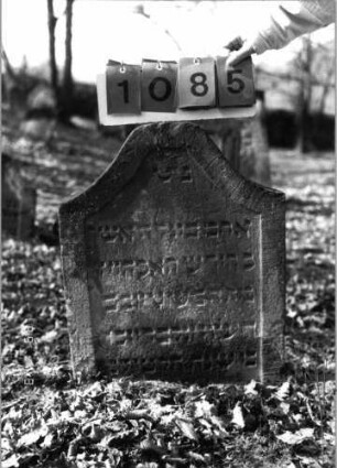 Grabstein 1085 (Index: 99753305) Material: Sandstein Zustand: leicht verwittert Maße HxBxT: 65x52x9 cm Beschreibung: Stele, giebelart. Abschl. , oben abgeflacht, Schriftfeld eingetieft: Grabstein 1085