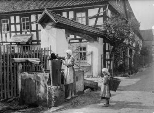 Am Brunnen in Breternitz bei Saalfeld : Breternitz. Frau und Kind an einem Brunnen Wasser schöpfend