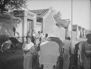 Reise nach China. Peking : Straßenbild mit langer Mauer, Passanten, Fahrrad- und Rikschafahrern
