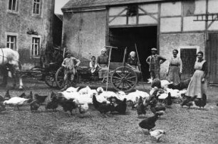Wilsdruff-Herzogswalde. Dorfmühle, Hof mit (v. r. n. links): Martha Träbert, Schwägerin Helene, Albin Träbert, Alexander Träbert als Kind auf dem Wagen, um 1918, Repro