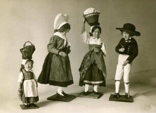 Vier Spielfiguren in handgefertigter Stoffkleidung, unterschiedlicher Größe, Trachtengruppe. Halbtotale