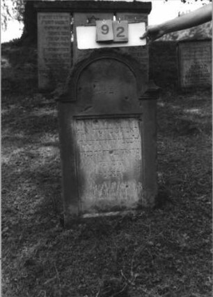 Grabstein 92 (Index: 100113881) Maße HxBxT: 93x56x11 cm Beschreibung: Stele, eingezogener Rundbogenabschluß: Grabstein 92