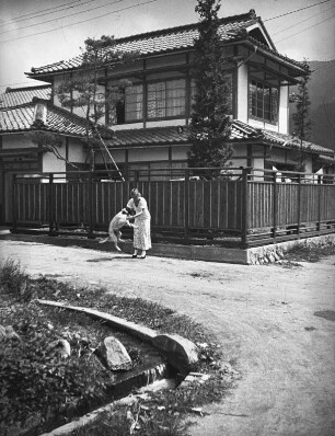Ōmachi. Wohnhaus des Fotografen. Straßenansicht mit Frau und Hund (wahrscheinlich Ehefrau des Fotografen)