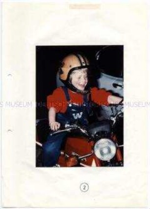 Kleiner Junge sitzt auf einem Moped (Altersgruppe bis 14)