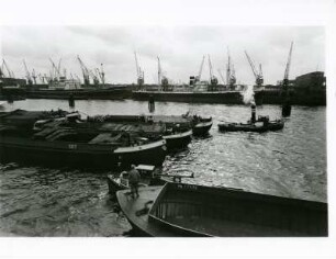 Hamburg. Hafen. Im Vierdergrund ein Schleppverband. Im Hintergrund Kaianlagen und Frachtschiffe