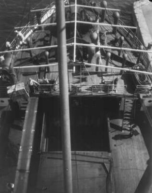 An Deck : Blick vom Oberdeck eines Schiffes auf das Holzdeck und den Bug.