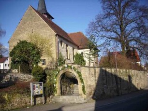 Ansicht von Westen mit Kirche (Langhaus einst fest mit Schlüsselloch-Schießscharte in Gebelwand des Speichergeschosses) über Kirchhofmauer