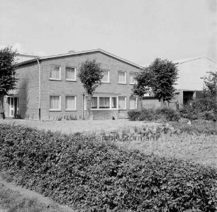 Bauerngehöft Leinius: Neubau: davor Garten mit Hecke und Bäumen