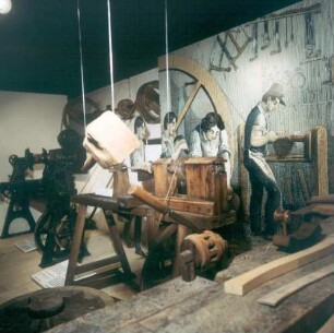 Rüsselsheim. Stadt- und Industriemuseum. Darstellung einer Stellmacherei (Wagnerei). Rechts Vergrößerung eines Holzstiches aus dem Jahre 1835 mit Darstellung der handwerklichen Arbeit durch den Menschen, rechts Mechanische Arbeit durch die Maschine