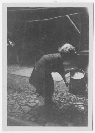Mädchen beim Leeren des Wassereimers im Hinterhof eines Hauses