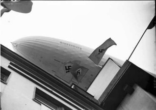 Berlin: Luftschiff Hindenburg über Amerikahaus (Teilsicht und Fahnen)