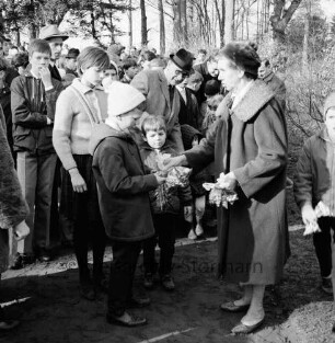 Schlosspark: Ostereiersuchen: Frau gibt Kindern Süßigkeiten
