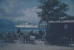 Reisefotos Griechenland. Strandcafé und vor der Küste ankerndes Passagierschiff "Milwaukee" (vielleicht im Mittelmeer)