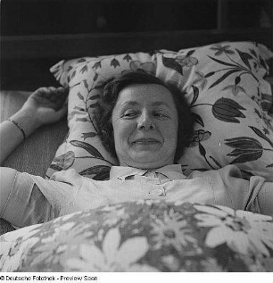Frau an Nähmaschine und im Bett
