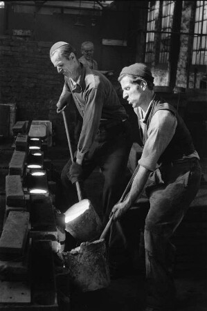 Radebeul. Eisengießerei, Handformgießen. Gießer füllen eine Form mit dem Handgießlöffel