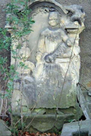 Grabstein an der Kirchenmauer: Darstellung Frau mit zwei Kindern