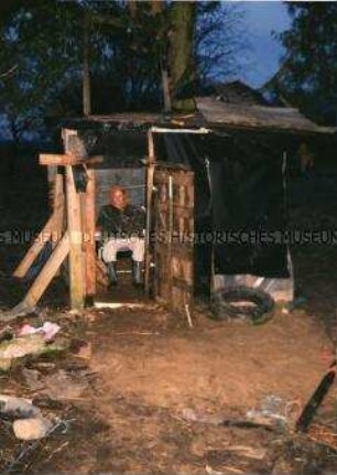 Junge in einer selbstgebauten Holzhütte im Wald (Sonderthema: Lebenskunst und Lebenskünstler)