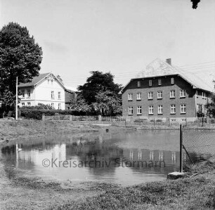 Feuerlöschteich: vorn rechts Zaun: im Hintergrund Bauerngehöfte mit Bäumen: Wettbewerb "Unser Dorf soll schöner werden"