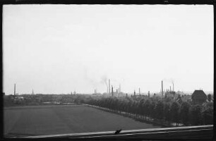 Blick aus dem Fenster eines Zugabteils auf das Panorama einer Landschaft mit industriellen Anlagen