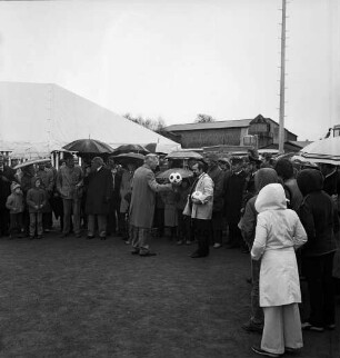 Dorferneuerung: Volksfest: Sportplatz: Einweihung: Überreichung von Fußbällen durch Bürgermeister Heinz Tebelmann an Sportvereinsvorsitzenden Schacht im Beisein von Landrat Hans-Henning Becker-Birck, Amtsvorsteher Friedrich Hardt, Amtsverwaltungsleiter Harry Baumann und Kreissportverbandsvorsitzendem Hans-Joachim Berg: dahinter Feuerwehrmannschaft und Zuschauer mit Regenschirmen: hinten Festzelt und Scheune