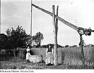 Spreewald? Zwei Bäuerinnen vor einem Brunnen stehend
