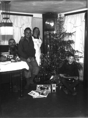 Familie mit Geschenken neben einem Weihnachtsbaum