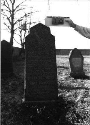 Grabstein 10 (Index: 100116087) Material: Granit, poliert Zustand: gut Maße HxBxT: 154x42x16 cm Beschreibung: aufgesockelte Stele mit rechteckig erhöhtem, giebelartigem Abschluß Symbolik: Traubenzweig: Grabstein 10