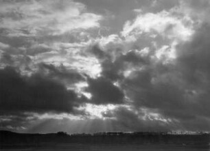 Wolkenbilder. Wolken mit untergehender Sonne über flacher Landschaft