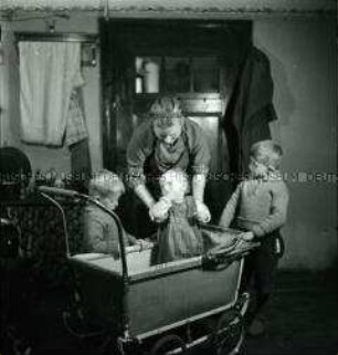 Arbeitsmaid des Reichsarbeitsdienstes bei der Kinderbetreuung in der Bauernküche