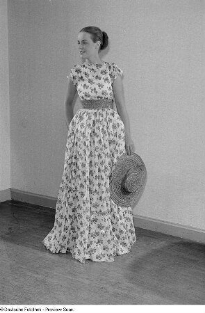 Eine Frau posiert mit Sommerkleid und Hut bei der "Internationalen Messemodenschau", Herbstmesse 1953