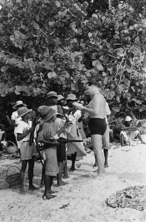 Reisefotos Karibik. Trinidad. Gruppe junger Muschelverkäufer mit europäischem Touristen in Badehose
