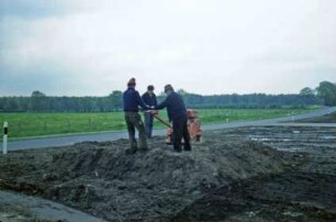 Bargfeld-Rögen: bei Elmenhorster Straße: Umsetzen von Meilenstein [Nr. 7]: neuer Standort: Arbeiter bei Planieren von Fundament