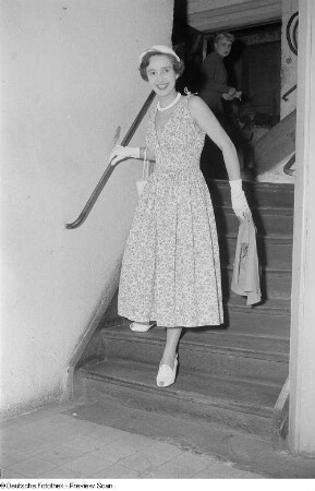 Eine Frau posiert mit Sommerkleid und Hut an einer Treppe bei der "Internationalen Messemodenschau", Herbstmesse 1953
