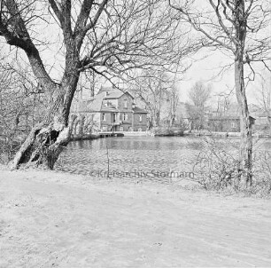 Mühlenteich: vorn Mühlenstraße: links und rechts Bäume und Sträucher: hinten Mitte Mühle: hinten rechts Schuppen