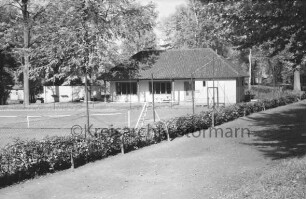 Kurpark: Gebäude des Tennis- und Hockey-Clubs "Blau-Weiß" e.V.: vorn Weg: links Tennisplatz hinter Zaun: hinten Bäume