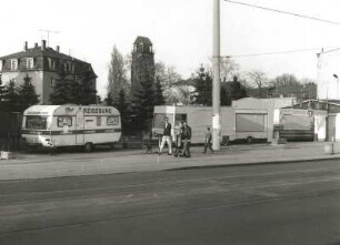 Dresden-Löbtau. Freifläche mit mobilen Verkaufsständen, Kesselsdorfer Straße zwischen Nr. 22 (Kaufhaus "Konsument") und Nr. 28. Straßenansicht von Südwest mit Turm der Friedenskirche