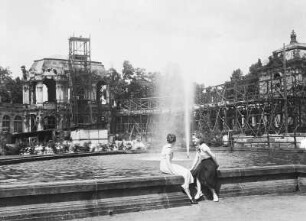 Zwei junge Frauen im Dresdner Zwinger, am Brunnen vor dem Wallpavillon sitzend : Dresden. Zwinger. Wallpavillon (eingerüstet), Wiederaufbau