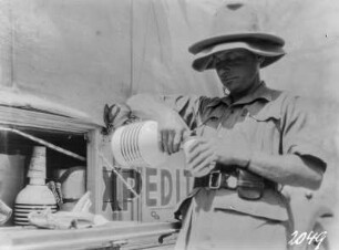 Afrika. Expeditionsmitglied an einem Expeditionswagen mit einer Wasserflasche. Werbung für Katadyn-Produkte, 1931