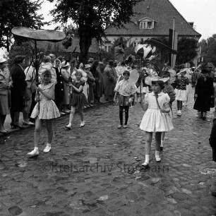 Karpfenfest: Umzug: Matthias-Claudius-Straße / Ahrensböker Straße (hinten rechts): Fußgruppe, Mädchen als Blüten, mit Seerosenknospen, Seerosenblättern: links am Straßenrand Zuschauer, Fahnenschmuck, 8. Oktober 1961