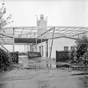 Franz-Kruse-Straße: Flugsicherungs-Funkmessstelle der Flughafenbetriebsgesellschaft Hamburg: vorn Einfahrt: rechts und links Jägerzaun und Büsche: hinten Gebäude mit Messstation