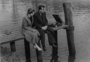 Ein junges Paar hört am Bootssteg Grammophonmusik