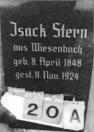 Grabstein 20 (Index: 100114959) Material: ? und polierter Granit Zustand: sehr gut Maße HxBxT: 189x65x24 cm Beschreibung: Stele auf gestuftem Sockel, im oberen Teil beidseitig schulterartig abgerundet, flacher Spitzgiebel mit Stern, eingesetzte Textplatte: Grabstein 20A