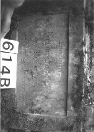 Grabstein 614 (Index: 99900671) Material: Sandstein, Marmortafel Zustand: leicht angewittert Maße HxBxT: 155x60x30 cm Beschreibung: aufgesockelte Stele mit Giebelaufsatz, in der Mitte rechteckig erhöht, oberer Abschluss mit Scheibenfries, im Giebelfeld Blüten, Schriftfeld von Säulen gerahmt Symbolik: Scheibenfries, Blüten: Grabstein 614B