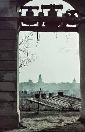 Lublin. Blick durch einen Torbogen mit Glockengeläut auf Stadtsilhouette