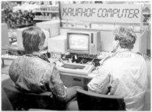 Rückenansicht von zwei jungen Männer, die im Kaufhaus einen Computer ausprobieren (Altersgruppe 14-17)