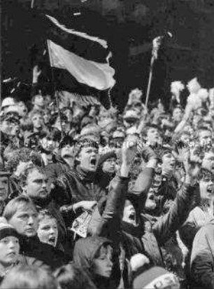 Enthusiastische Fußballfans mit Fahne (Altersgruppe 18-21)