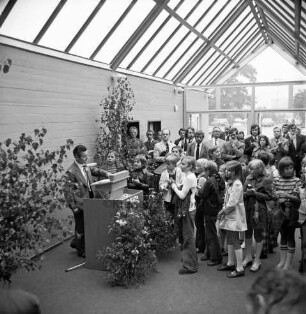 Schulzentrum Reinbek: Mühlenredder: Hauptschule [später: Hertzig-Schule, dann zusammen mit Realschule Reinbek Gemeinschaftsschule Reinbek]: Neubau: Einweihung: Innenansicht: Pausenhalle: Rede des Landesministers für Kultur Walter Braun, am Rednerpult zwischen Grünpflanzen: rechts Schüler, Lehrer und Gäste