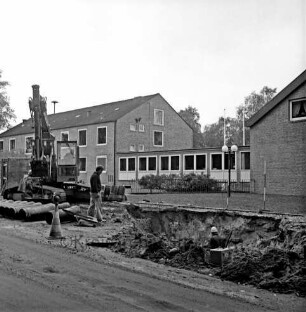 Abwasser: Ausbau der Kanalisation: Wöhrendamm: vorn rechts Baugrube: darin Arbeiter: links Bagger: daneben weiterer Arbeiter: hinten links Rathaus: in der Mitte Verbindungstrakt: rechts Waldreitersaal