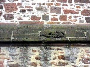 Totenkirche (Romanische Gründung)-Querhaus Nord im Norden-Figurenrelief (liegender Mann in Hochrelieftechnik) auf Wasserschlag im Detail